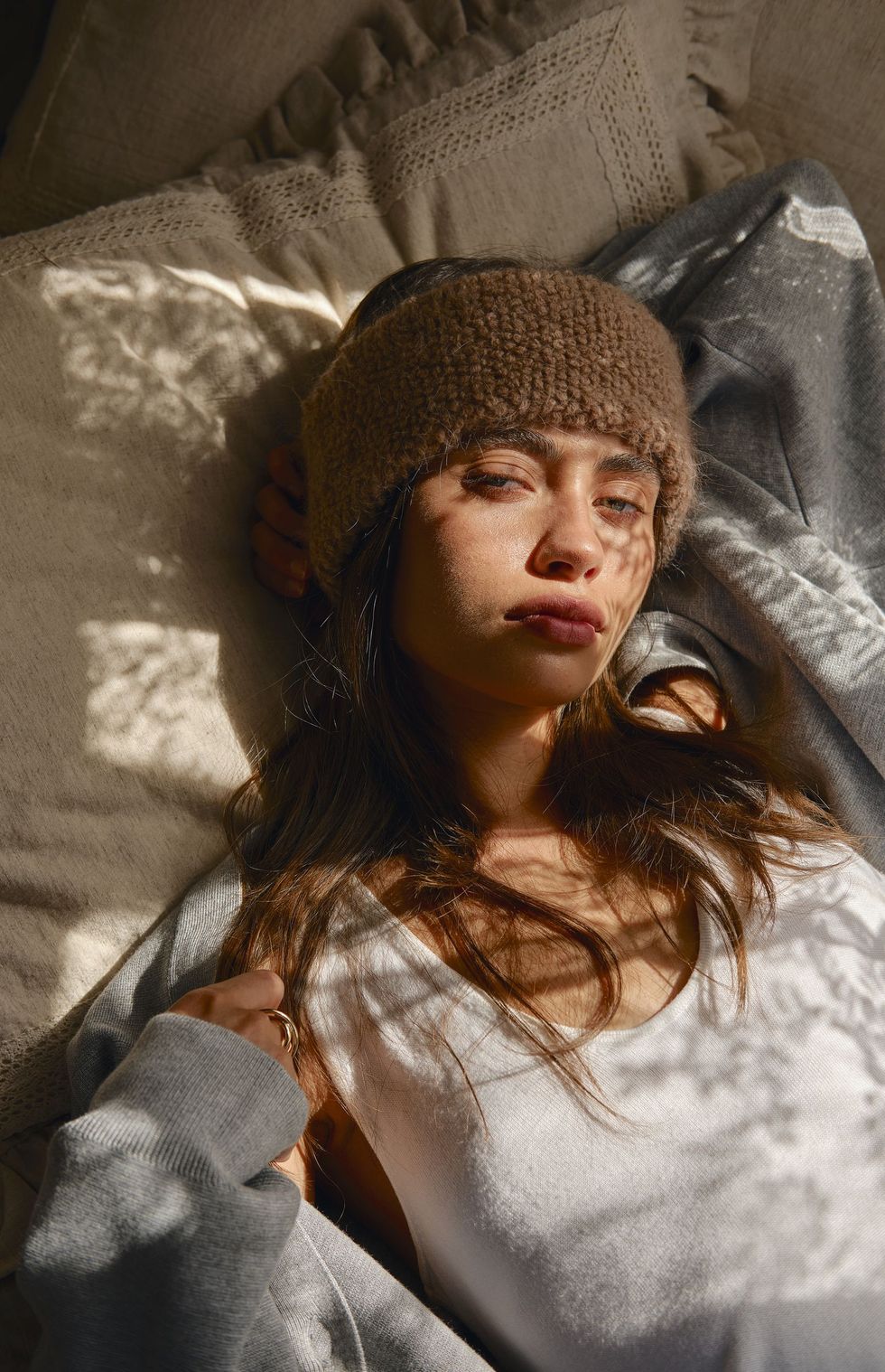 Model lying on linen in a knitted headband