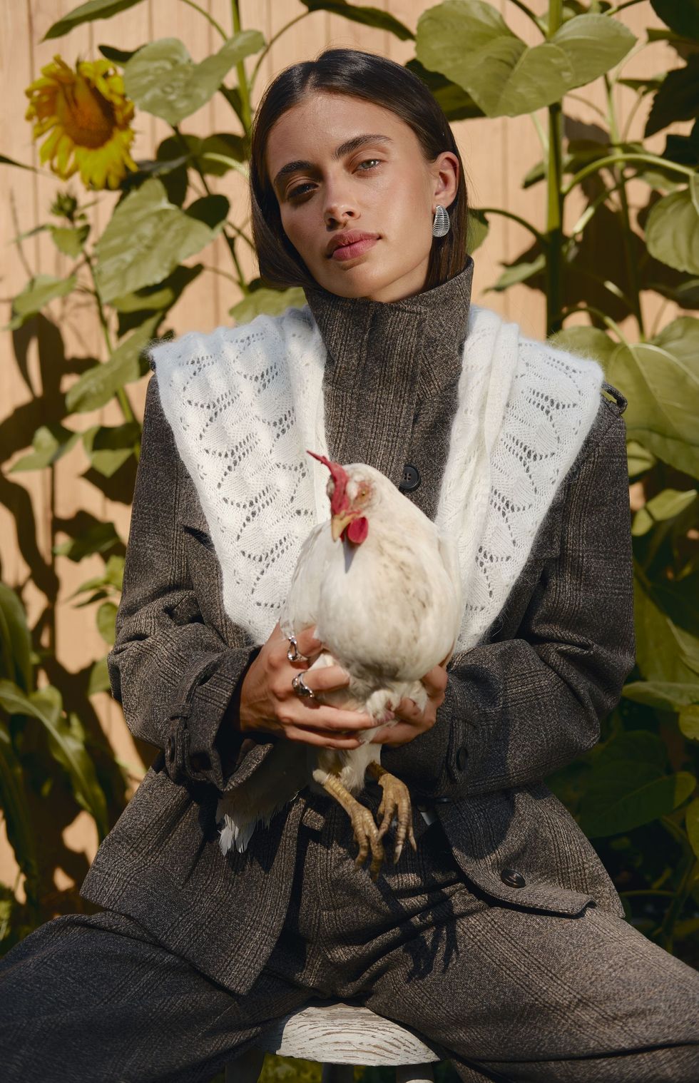 Model holding a white hen in a tweed suit