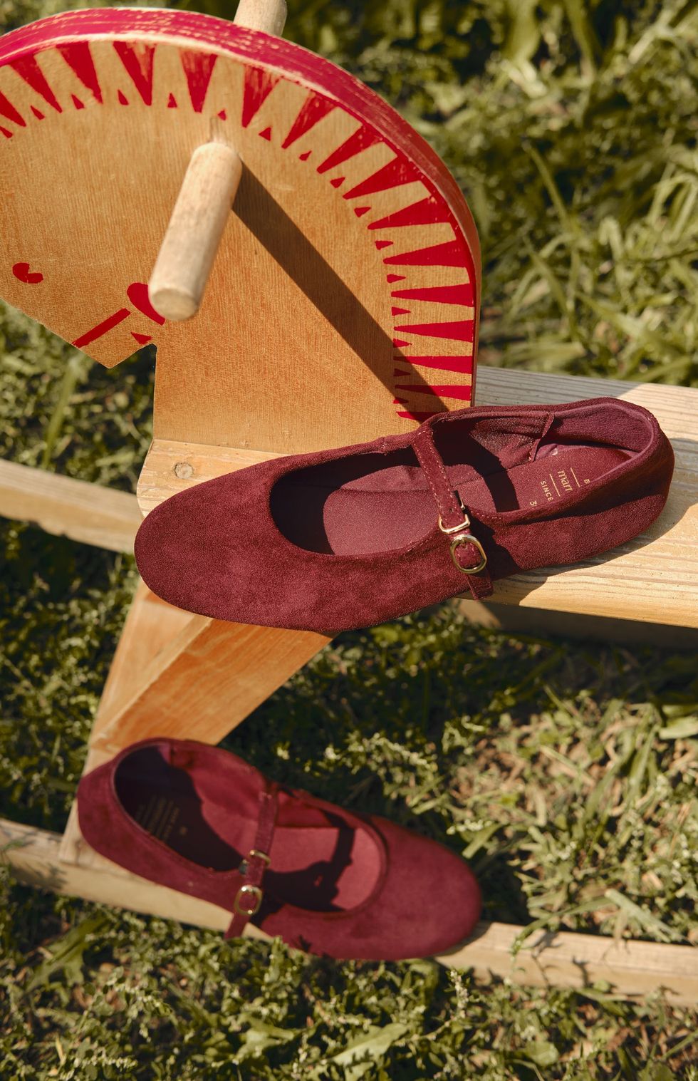 Burgundy suede Mary Janes on a bench